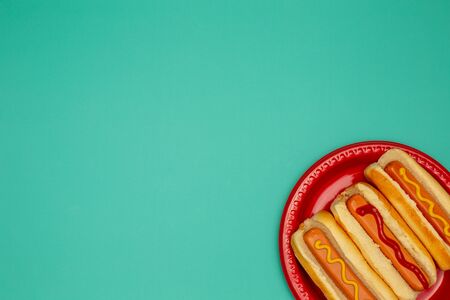 three hot dogs on a red plate colorful tableの写真素材