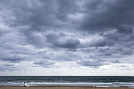 man walking on the beach with surf boardの写真素材