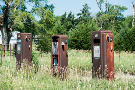 Three rusty old abandoned gas pumps at a roadside service stationの写真素材