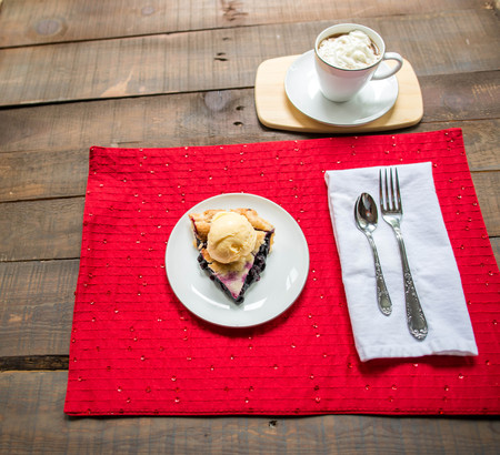 Blueberry pie with vanilla ice cream and coffee with whip cream on topの写真素材