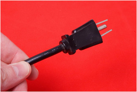 a hand holds out a plug over red
