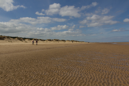 Sand dunes and people walking on the beach at Wells-next-the-Sea, Norfolkの写真素材