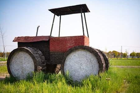 Old tractor in the field with red brick wall and green grass.の写真素材