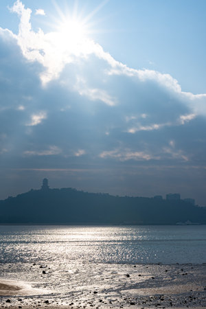 Sunset over the sea with the silhouette of the city in the backgroundの写真素材