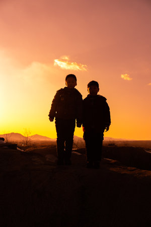 Silhouette of a man and woman at sunset in the mountainsの写真素材