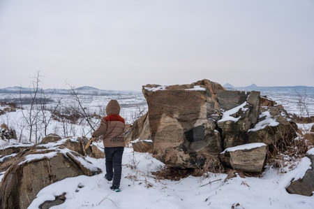 Little girl with ax in the mountains in winter. Winter landscape.の写真素材