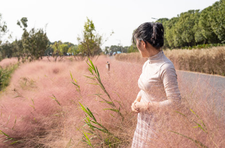 Rear view of a woman standing in a field of pink grassの写真素材