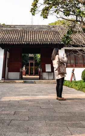 Asian woman taking a photo with mobile phone in a Chinese temple.の写真素材