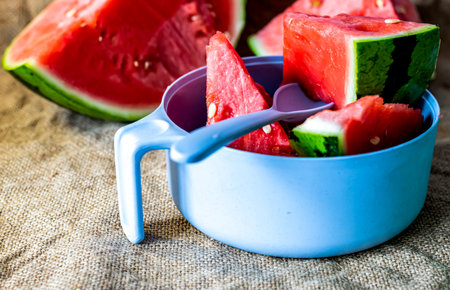Slices of watermelon in a blue bowl on a burlap backgroundの写真素材