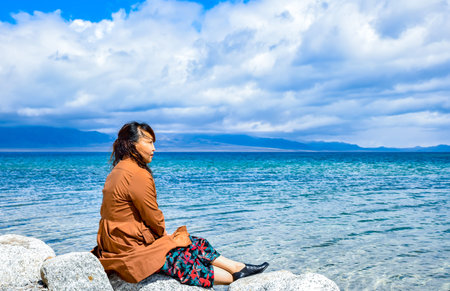 Young woman sitting on a rock by the sea in Hawaii, USA