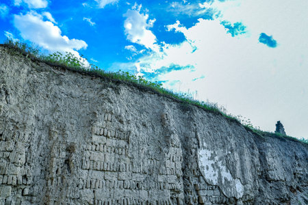 Stone wall with green grass and blue sky in the background, Thailand.