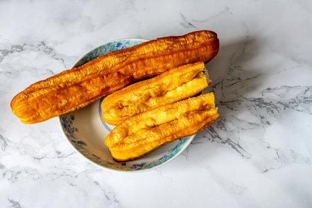 Thai dessert - deep fried banana on ceramic plate on white marble backgroundの写真素材