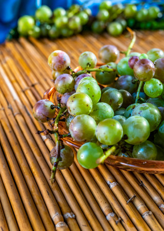 Grapes in a clay bowl on a bamboo tablecloth.の写真素材