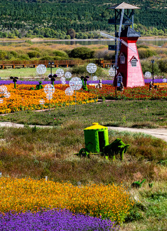 Blooming spring garden with windmill and flowers in sunny day.の写真素材