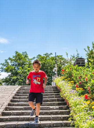 Asian boy walking up the stairs in the park with blue sky.の写真素材