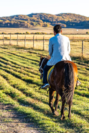 Young man riding a horse on a farm in the countryside in autumnの写真素材
