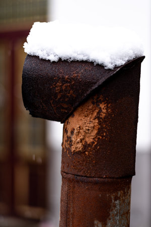Close up of a rusty pipe covered with snow on a city streetの写真素材