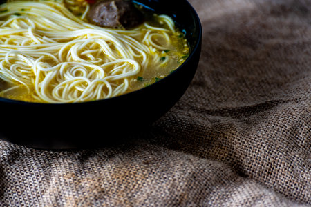 Noodles soup with meat in a bowl on sackcloth backgroundの写真素材