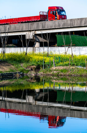 Freight train on the bridge over the river, reflection in the waterの写真素材