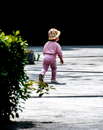 baby girl walking in the park with black background and shadow.の写真素材