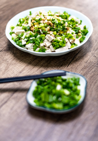 Fresh chinese onion salad with tofu and sesame seeds on wooden backgroundの写真素材