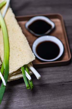 Crispy crepes with green onions and soy sauce on wooden backgroundの写真素材