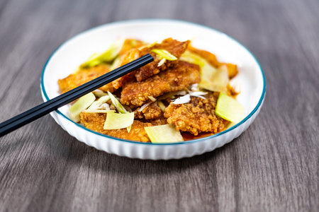 Fried fish in a bowl with chopsticks on a wooden tableの写真素材