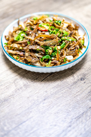 Fried anchovies with chili sauce in a bowl on wooden backgroundの写真素材