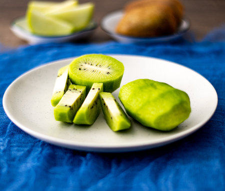 kiwi and kiwi slices on a plate on a blue background