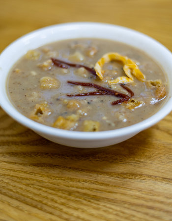 A bowl of chinese soup on a wooden table, close upの写真素材