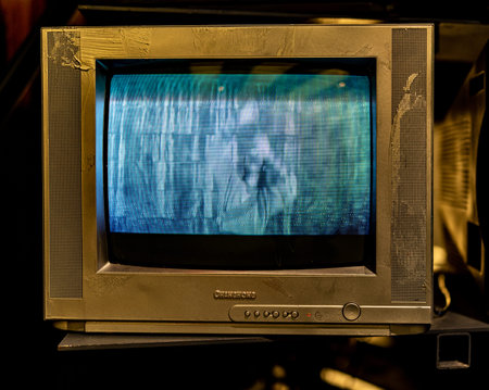 Old TV set with blue screen on black background. Selective focus.