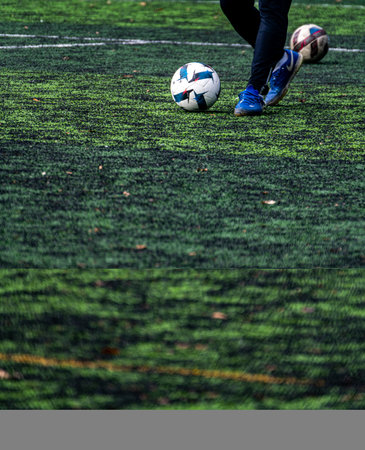Soccer player with ball on the green artificial turf of soccer fieldの写真素材