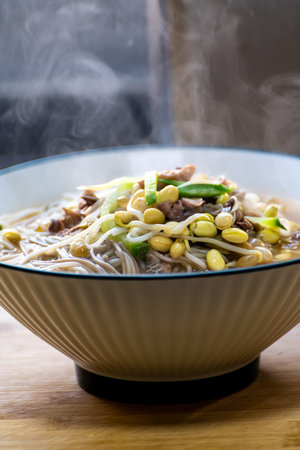 Chinese noodle soup with beef and vegetables in a bowl on wooden tableの写真素材