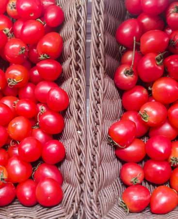 Ripe red cherry tomatoes in wicker basket. Top view.の写真素材