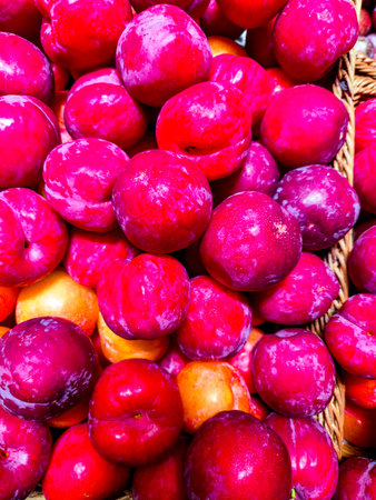 Fresh plums in a basket on the counter of a farmers marketの写真素材