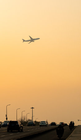 Airplane in the sky over the road at sunset time. Travel conceptの写真素材