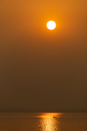 Beautiful sunset at the sea with orange sky and silhouette of fishermanの写真素材