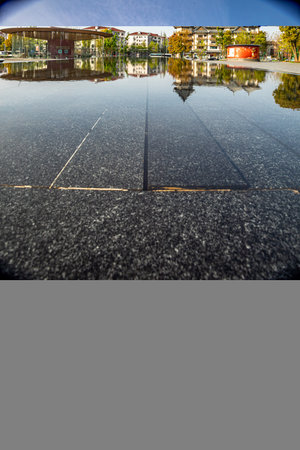 Asphalt road with reflection in the city center, closeup of photoのeditorial素材