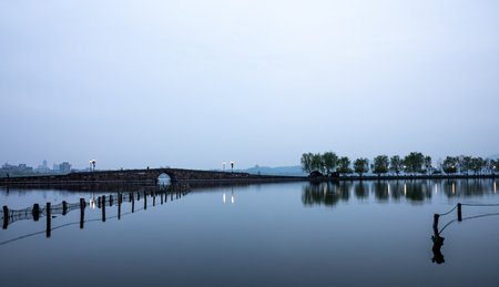 The old wooden bridge across the river at dusk in Hangzhou, Chinaの写真素材