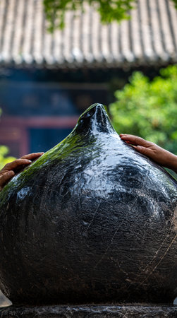 Hands of a Buddhist monk pouring water from a pot in a templeの写真素材