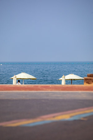 Two white umbrellas on the promenade near the seaの写真素材