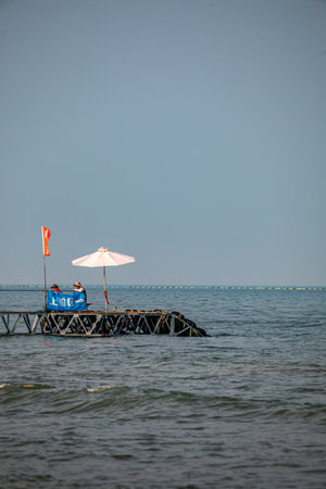 Wooden jetty in the sea with red and white umbrella.のeditorial素材