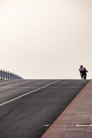 Rear view of a child riding a bicycle on the bridge.の写真素材