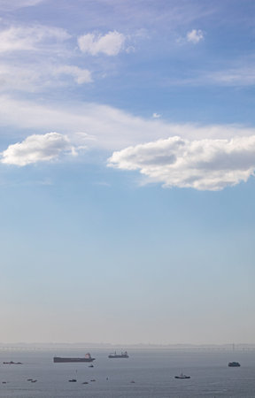 Cargo ships in the sea and blue sky with white clouds.