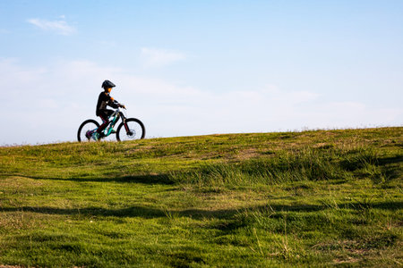 Cyclist Riding a Mountain Bike on a Green Grassy Hill