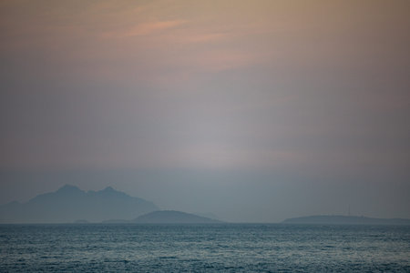 Beautiful sunset over the sea with mountains in the background. Toned.