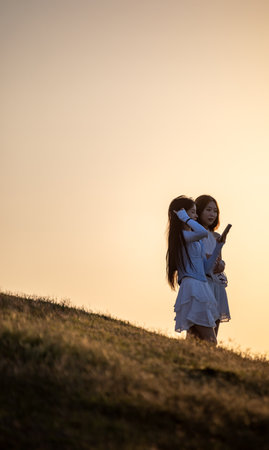 Mother and daughter playing on the meadow at sunset. Concept of friendly family.の写真素材