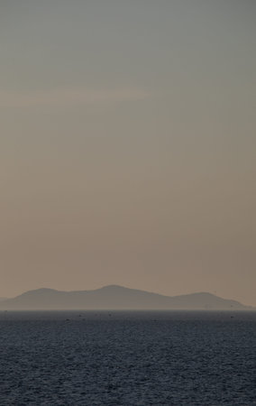 Seascape with sea and mountains in the background at sunset.