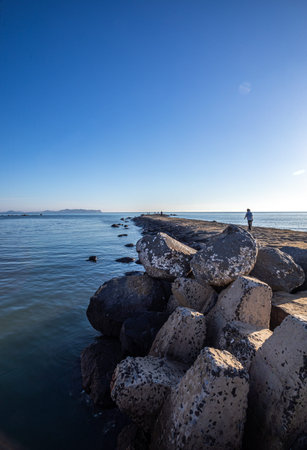 Lonely man standing on the rocks on the seashore
