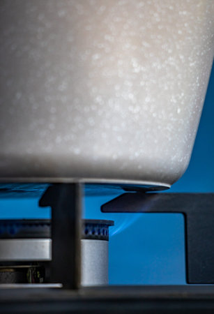 Close-up of a gas burner in a kitchen. Blue background.